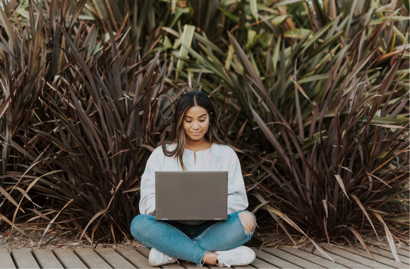 A pleased and relaxed young woman joins class virtually from a tropical boardwalk (that also has wifi).